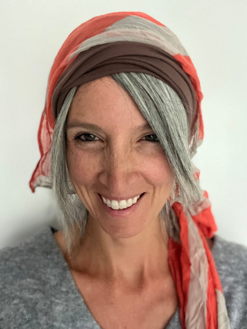 Juliet demonstrating grey human hair wig hat with pink scarf over brown softie