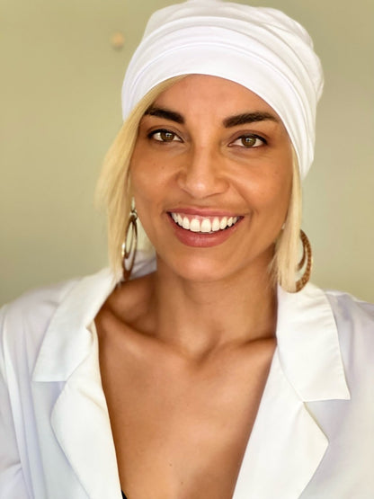 Model wears blonde headband wig under a white beanie for cancer patients
